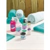 The image shows an arrangement of skincare products, including hand and face washes, body cream, and face cream, along with rolled turquoise towels.