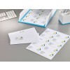 The image shows various papers with a logo and addresses. There is an envelope with a corresponding label. The documents are organized in a bright blue folder, next to a keyboard and a pen holder.