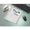 The image shows a workspace with a transparent folder containing a brochure for holiday homes, a stapler, a computer keyboard, and a mouse on a sleek surface.