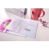 The image shows two envelopes with a floral design, a pink mug, a metal holder, and some candies on a table.