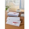 The image shows several unopened envelopes with addresses on the front, and a computer with a word processor. Next to them, there is a cup of coffee and a vase with flowers on a desk.
