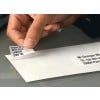 A hand removing a label with address information from an envelope. The label contains information about London, England, and the other part has an address in Paris, France.