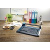 In the image, a desk can be seen with a paper cutter, a cup of coffee, cookies on a plate, a mobile phone, a water bottle, writing tools, and document organizers in various colors, along with a decorative plant.