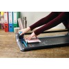 The image shows a person using a paper cutter on a table. There are colored folders in the background, a cup, and a water bottle.