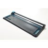 The image shows a sleek paper trimmer with a cutting blade and measurement markings on a grid surface, designed for precise cutting tasks.