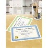 The image displays two certificates of excellence on a table. One certificate is green and the other is blue, both recognizing someone for their communication skills, awarded on October 12, 2012. There is also a glass container filled with pencils and pens next to the certificates.