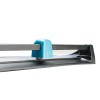 The image shows a close-up of a paper cutter, specifically the blade and guide mechanism, with a blue plastic handle and metallic rail.
