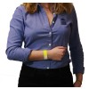 The image shows a woman wearing a blue shirt with a logo. She is holding her wrist, which has a yellow wristband on it.