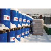 The image shows blue barrels containing hazardous substances in a snowy environment, with stacks of wooden pallets and some green barrels in the background.